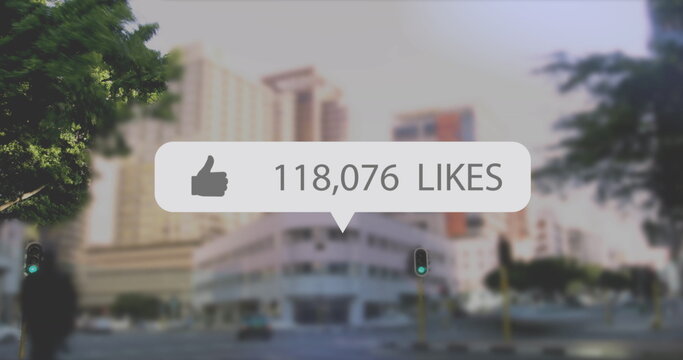 Image of digital interface thumbs up with growing numbers on white speech bubble over cityscape