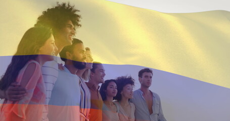 Image of flag of colombia waving over diverse friends forming human chain and looking at sea