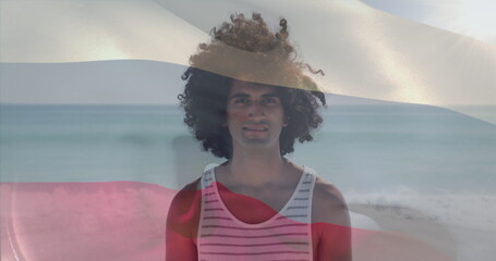 Image of russian flag waving over smiling biracial man standing on beach against sea