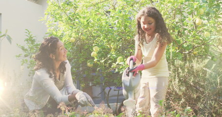 Image of lights over happy biracial woman and girl watering garden