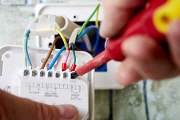 Connecting colored wires to terminals of thermostat for floor heating.