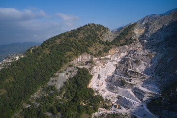 Fototapeta na wymiar Carrara marble quarry in Italy with working bulldozers. Marble quarry top view. aerial panorama of marble quarries Carrara Italy.