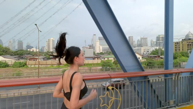 Woman jogging on the bridge at morning time in the city. slow motion 4k video,