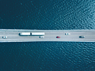 Aerial view of bridge road with cars and truck over lake or sea in Finland