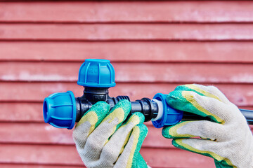 Plastic pipe tee connector fitting with compression clamp joint in hands of plumber on background...