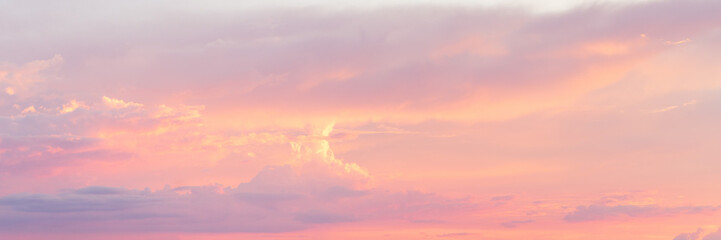Sky clouds at sunset in summer. Panoramic cloudscape in pastel colored orange to pink gradient .