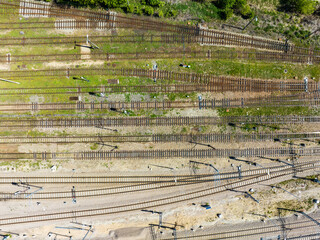 Old and new, active and destroyed railroad tracks.  Concrete, rusty, wooden or missing ties. Electric traction and signal lights. Aerial view from above. Good for background