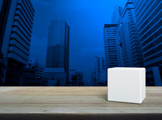 White block cube on wooden table over modern office city tower and skyscraper