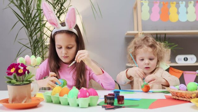 Traditional egg coloring activity for kids. Kid's anticipation of Easter egg decoration. Easter egg for the party. Cute children painting easter egg preparing for holiday in home interior