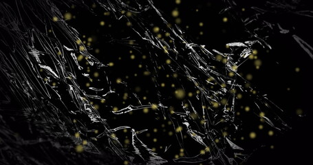 Image of yellow particles floating over light on moving shiny black plastic