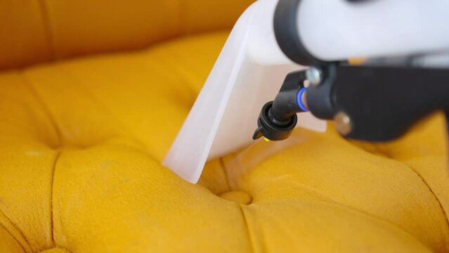 Detailed close-up of professional equipment in action as it dry cleans sofa upholstery.