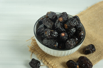 Closeup delicious Kurma or sweet dried date palm fruits on white bowl. Much sought after during Ramadan to break the fast.