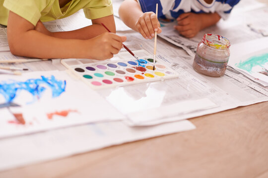 Children hands, palette and creative with paint brush on floor or playing, hobby and drawing together at home. Kids, motor skills and growth for childhood development with creativity for artwork