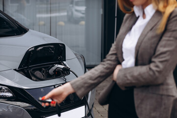 Woman holding socket and charging electric car