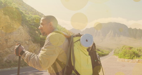 Image of light spots over biracial man walking in mountains - Powered by Adobe