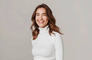 A woman is smiling and wearing a white shirt. She is standing in front of a white background