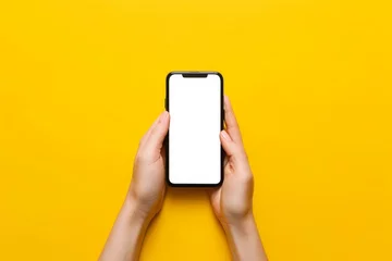 Foto op Aluminium A person is holding a cell phone with two hands with a yellow background © Bambalino Studio