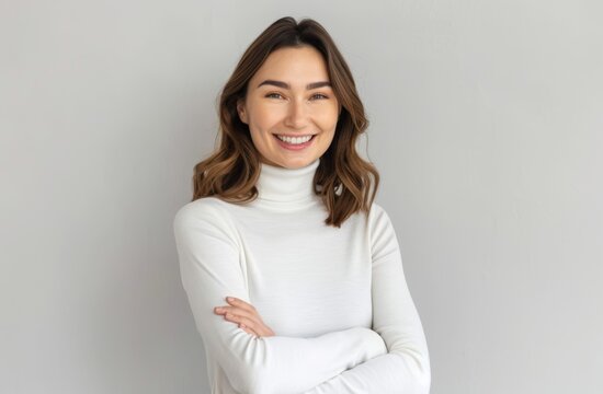 A woman is smiling and wearing a white sweater. She is posing for a picture. Concept of warmth and happiness