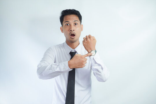 Adult Asian man showing angry face expression while pointing to his arm watch	