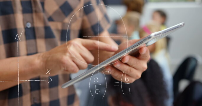Image of mathematical equations over caucasian male teacher using tablet