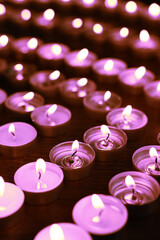 Beautiful burning violet candles on black background. Funeral attributes