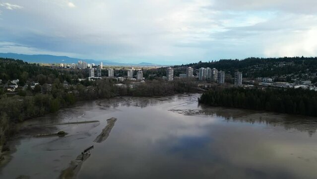 Ocean shore with mud in the city. Homes on the coast, trees and mountains. Cloudy overcast sky. Aerial background.