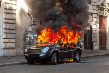 Burning suv car damaged in isolated city street before being rescued by firefighters for explosion danger