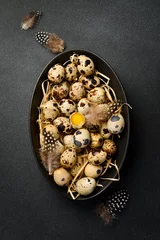 Foto op Plexiglas Fresh quail eggs in a black stone bowl. Quail feathers. On a black stone background. Top view. © Yaruniv-Studio