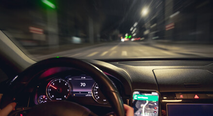 Car steering wheel and view of the night road from the car, close-up. © puhimec