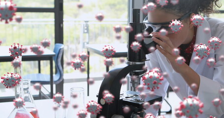 Coronavirus research depicted with cells over a female scientist using a microscope.