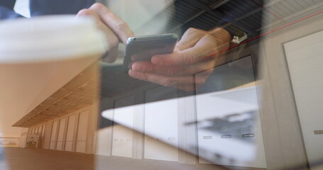 Image of man using smartphone over warehouse in background