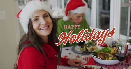 Image of happy christmas text over caucasian family wearing santa hats