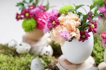 Florist at work: woman shows how to make simple Easter decoration with egg shell and various flowers.