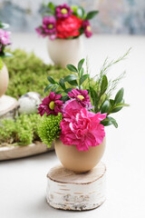 Florist at work: woman shows how to make simple Easter decoration with egg shell and various flowers.