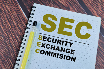 Concept of SEC - Security Exchange Commision write on book isolated on Wooden Table.