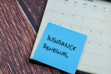 Concept of Insurance Renewal write on sticky notes isolated on Wooden Table.