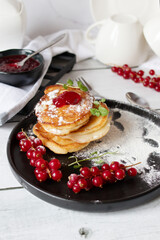 Pancakes with red currants and jam. on a black plate. dessert