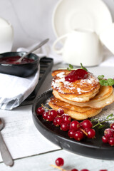 Pancakes with red currants and jam. on a black plate. dessert