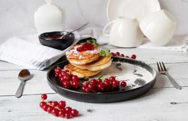 Pancakes with red currants and jam. on a black plate. dessert