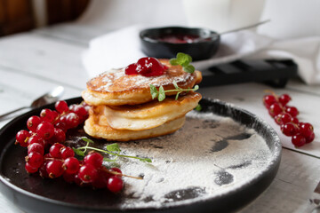 Pancakes with red currants and jam. on a black plate. dessert