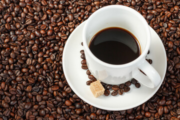 A cup of coffee with coffee beans and sugar cubes.
