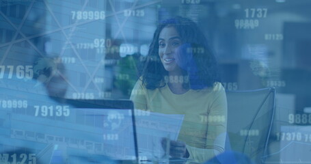 Image of numbers changing over happy biracial woman in office