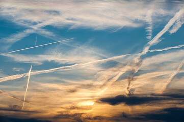 Morgen- oder Abendhimmel mit auf- oder untergehender von den Wolken verdeckter Sonne und Gewirr von...