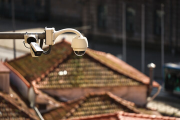 Surveillance camera. CCTV camera used to watch over citizens in a city. Photo of a surveillance camera over the roofs.