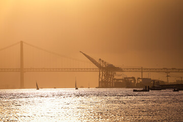 Sunset over Port of Lisbon. Lisbon port cranes and 25 April landmark bridge in Background. Travel...