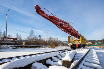 A track-laying monument dedicated to the construction of the Baikal-Amur Mainline (BAM). Severobaikalsk city, Republic of Buryatia, Siberia, Russia. View of a laying crane on rails among the snow.