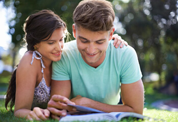Happy, grass and couple with books for reading, learning and studying together outdoors at college. University, education and man and woman with textbook in park for bonding, relax and rest on campus