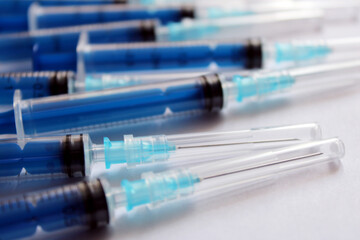 Many blue medical syringes on a white background.