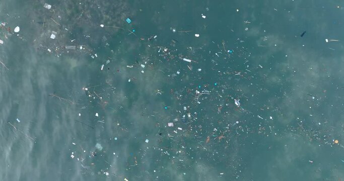 Top down drone shot of polluted water filled with plastic trash and dead coral reef in the turqouise tropical water of Balangan Beach Uluwatu Bali Indonesia