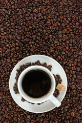 A cup of coffee with coffee beans and sugar cubes.